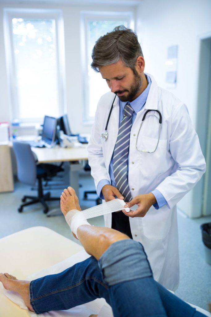 Doctor bandaging foot of patient